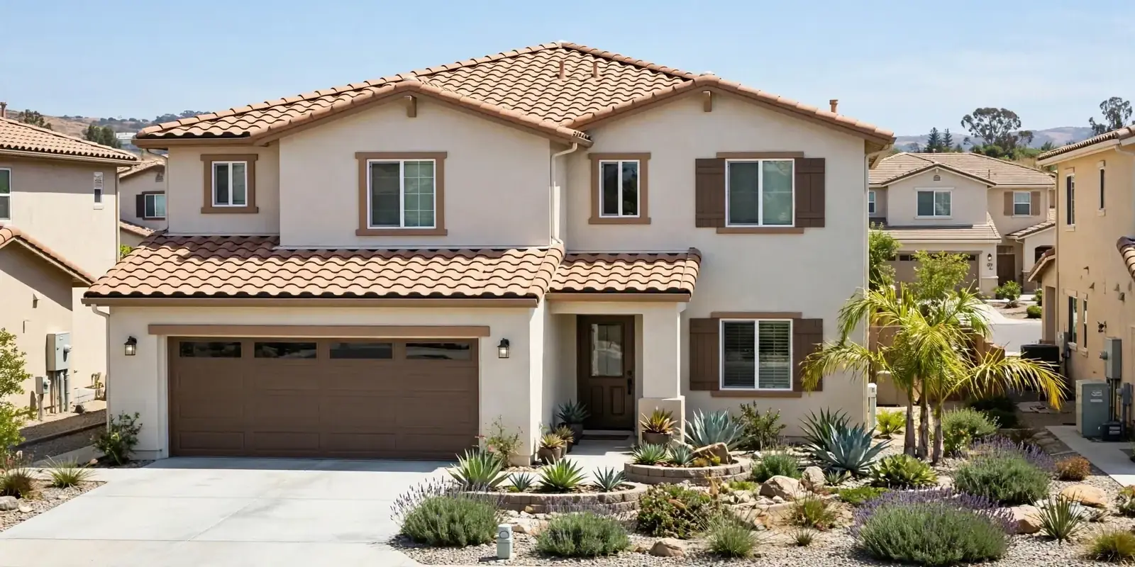 Two story stucco house with a tile roof, garage and drought tolerant front landscaping